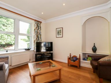 A living room with a television on a stand beside a window and a coffee table in the center at Silver How in Ambleside