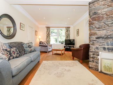A living room with sofas a stone fireplace wooden floor and a television at Silver How in Ambleside