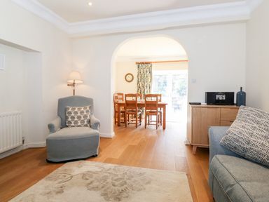 A sitting room with an armchair a lamp a rug a wooden sideboard and a dining area visible through an arch at Silver How in Ambleside