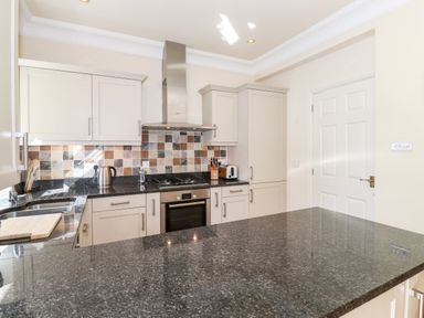 A kitchen with black granite countertops white cabinets a stove oven and tiled backsplash at Silver How in Ambleside