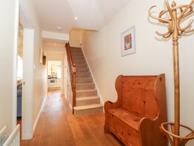 A hallway with wooden floor a staircase a wooden bench and a coat rack at Silver How in Ambleside