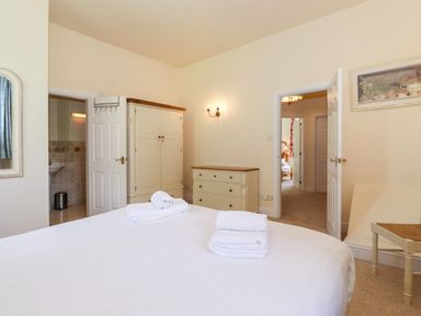 A bedroom with a bed with folded towels a wardrobe a chest of drawers two open doors and a chair at Silver How in Ambleside