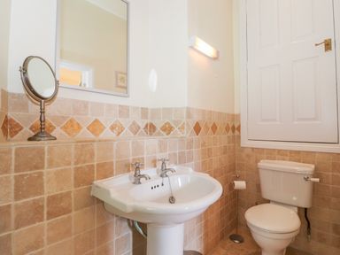 A bathroom with a pedestal sink mirror toilet and wall tiles at Silver How in Ambleside