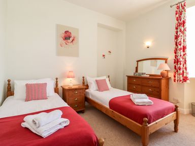A bedroom with two single beds a wooden dresser and a window with floral curtains at Silver How in Ambleside