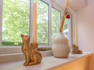 A windowsill with two animal-shaped candle holders and a vase with dried flowers at Rookery Cottage in Kelsale near Saxmundham