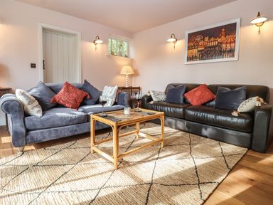 A living room with two sofas a wooden coffee table and a rug at Rookery Cottage Kelsale near Saxmundham