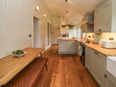 A kitchen with wooden countertops cabinets and a wooden dining table with a bench at Rookery Cottage in Kelsale near Saxmundham