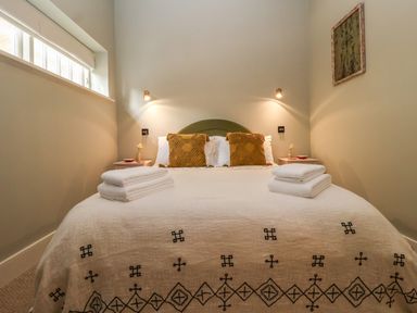 A bedroom with a bed with patterned blanket two pillows and folded towels on the bed at Rookery Cottage in Kelsale near Saxmundham