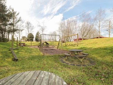 A playground area with swings and picnic tables on a grassy field at Matfen in Longframlington