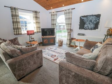 A living room with two sofas a television a rug and plaid curtains at Matfen in Longframlington