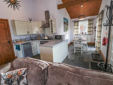 A kitchen and dining area with wooden ceiling and checkered curtains at Matfen in Longframlington