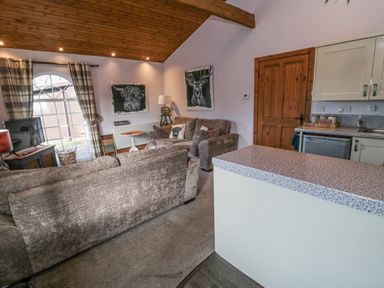 A living room with sofas paintings and a kitchen counter at Matfen in Longframlington