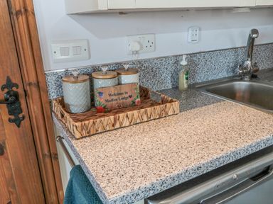 A kitchen countertop with three jars in a woven tray and a welcome sign next to a sink at Matfen Lodge in Longframlington