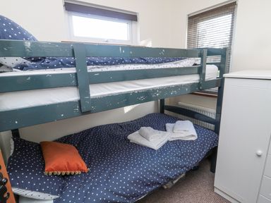 A bunk bed with navy blue polka dot bedding and white towels on the lower bed beside a white cabinet in a bedroom at Matfen in Longframlington