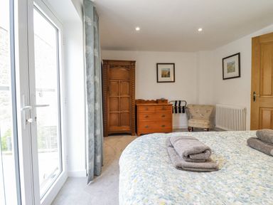 A bedroom with a bed and wardrobe at Neptune Cottage in Conwy