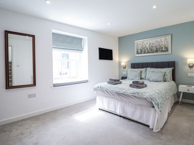 A bedroom with a bed and mirror at Neptune Cottage Conwy