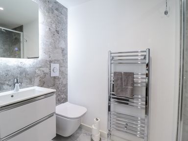A bathroom with a sink, toilet, and towel rail at Neptune Cottage in Conwy