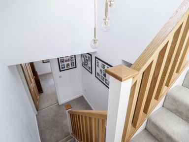A staircase with framed pictures in the hallway at Neptune Cottage in Conwy