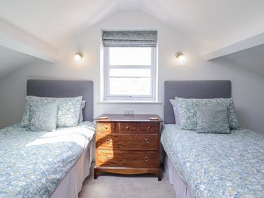 A bedroom with two beds and a wooden chest of drawers at Neptune Cottage in Conwy
