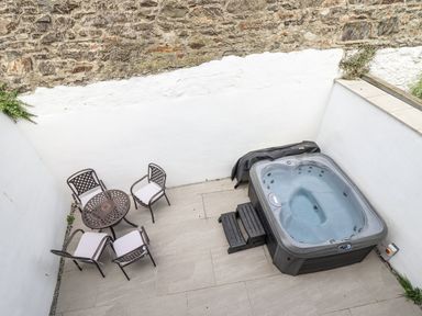An outdoor area with a hot tub and seating at Neptune Cottage in Conwy