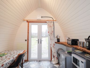 A kitchen with a dining table and double doors at Pod 2 in Beauly