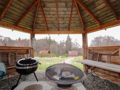 An outdoor structure with a fire pit and grill at Pod 2 in Beauly