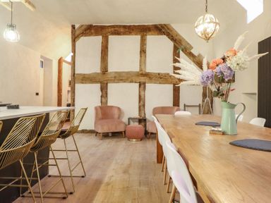 A dining room with a wooden table and bar stools at Godre'r Gyrn, Plas Moelfre Hall Barns, Oswestry