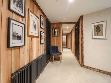 A hallway with frames on walls and a chair at Godre'r Gyrn, Plas Moelfre Hall Barns in Oswestry