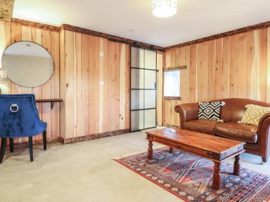 A living room with wood paneling and furniture at Godre'r Gyrn, Plas Moelfre Hall Barns, Oswestry