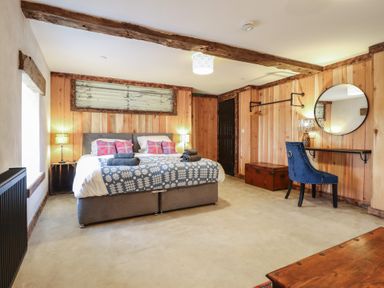 A bedroom with a bed, table, chair and lamp at Godre'r Gyrn, Plas Moelfre Hall Barns in Oswestry
