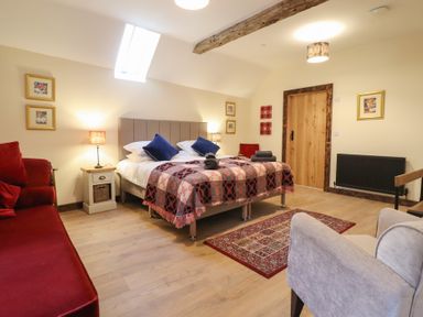 A bedroom with a bed and sofa at Godre'r Gyrn, Plas Moelfre Hall Barns, Oswestry
