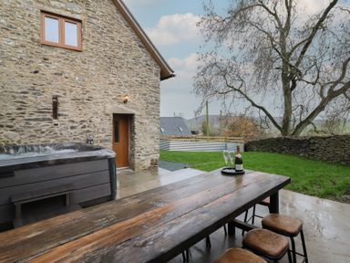 An outdoor area with a hot tub and dining table at Godre'r Gyrn, Plas Moelfre Hall Barns, Oswestry