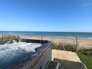 A hot tub on a patio overlooking a sandy beach and the sea at Beach Haven in Happisburgh East Anglia