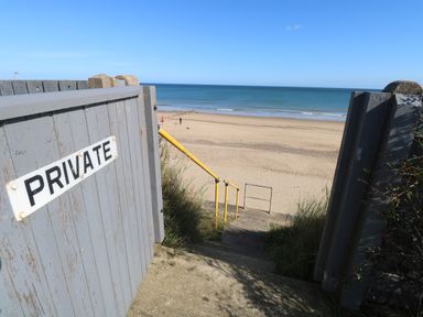Stone steps with yellow railing leading to a sandy beach and ocean beyond at Beach Haven in Happisburgh East Anglia