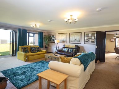 A living room with sofas a coffee table blue curtains and a rug at Beach Haven in Happisburgh East Anglia