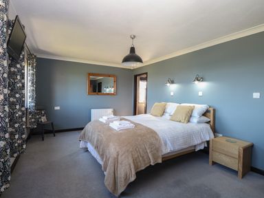 A bedroom with a double bed two pillows bedside table mirror on the wall and a chair at Beach Haven in Happisburgh East Anglia