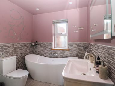 A bathroom with a toilet bathtub sink and window at Beach Haven in Happisburgh East Anglia