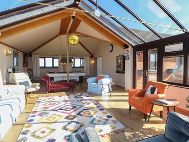 A living room with colorful chairs a pool table and a glass roof at Beach Haven in Happisburgh East Anglia