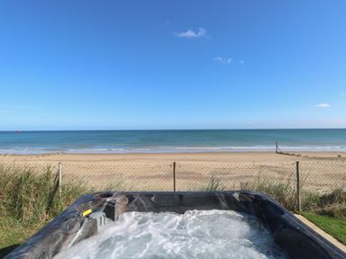 A hot tub overlooking a sandy beach and the ocean at Beach Haven in Happisburgh East Anglia