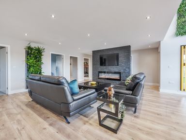 A living room with black leather sofas a glass side table a wall-mounted tv and an electric fireplace at Micklemore Lakes and Lodges in North Thoresby