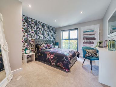 A bedroom with a floral bedspread a blue chair a full length mirror and a window at Micklemore Lakes and Lodges in North Thoresby