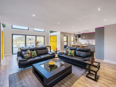 A living room with black leather sofas and a coffee table next to an open kitchen at Micklemore Lakes and Lodges in North Thoresby