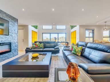 A living room with two black leather sofas and a glass coffee table at Micklemore Lakes and Lodges in North Thoresby