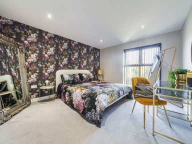 A bedroom with floral wallpaper and bedding a large mirror a glass desk and yellow chair at Micklemore Lakes and Lodges North Thoresby