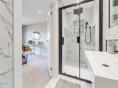 A bathroom with a glass shower enclosure and a white sink next to a room with a desk chair and a round wall mirror at Micklemore Lakes and Lodges North Thoresby