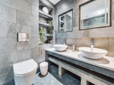 A bathroom with two sinks a toilet shelves with towels and plants and two mirrors at Micklemore Lakes and Lodges in North Thoresby