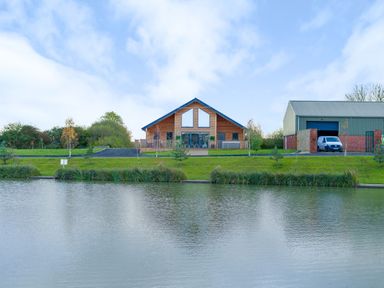 A wooden lodge and a large garage by a lake at Micklemore Lakes and Lodges in North Thoresby
