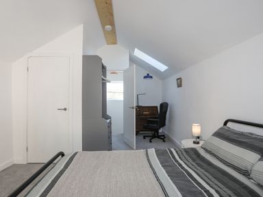 A bedroom with a bed desk chair wardrobe and lamp at 4 Ty Person in Braichmelyn near Bethesda