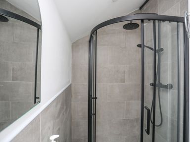 A bathroom with a glass shower enclosure and a wall mirror at 4 Ty Person in Braichmelyn near Bethesda