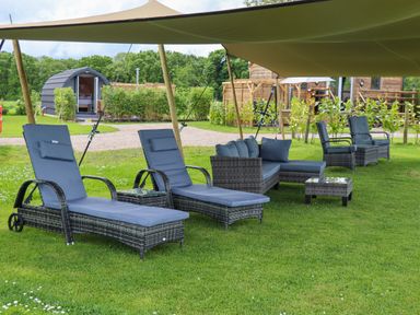 Outdoor patio furniture including lounge chairs, a sofa, and side tables under a canopy on grass at Moel Y Parc in Bryniau Clwyd near Denbigh